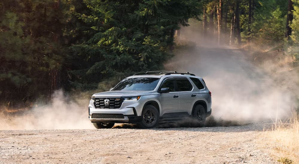 A grey 2025 Honda Pilot Trailsport is off-roading on a dirt lot.