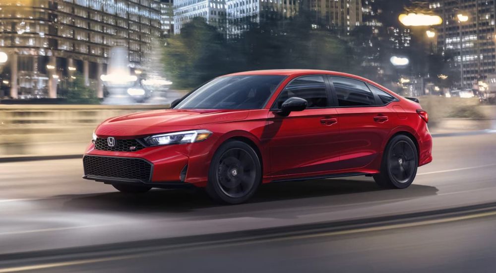 A red 2025 Honda Civic Si driving on a city street.
