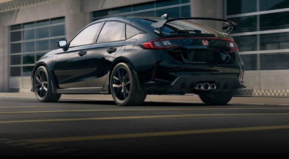 A black 2025 Honda Civic Type R in front of garage bays.