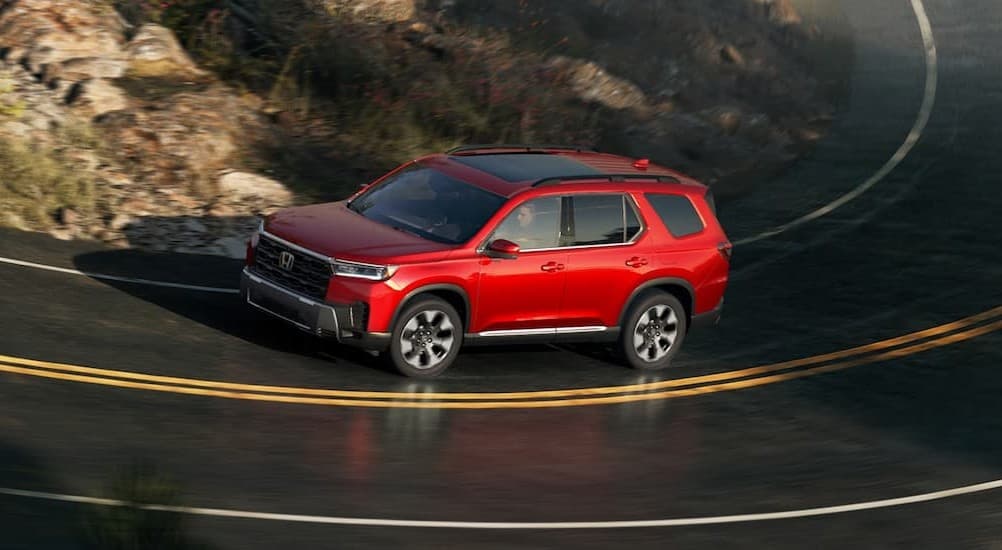 A red 2026 Honda Pilot for sale driving on a highway.