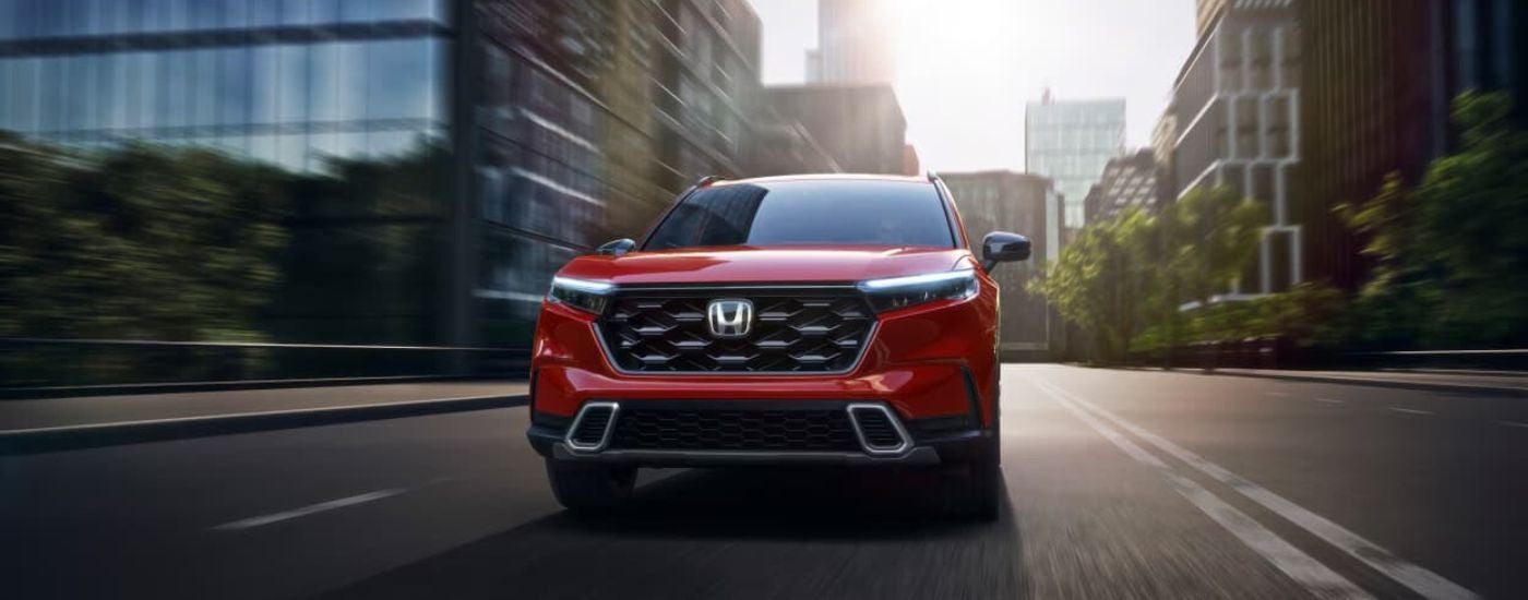Red 2024 Honda CR-V driving on a city street