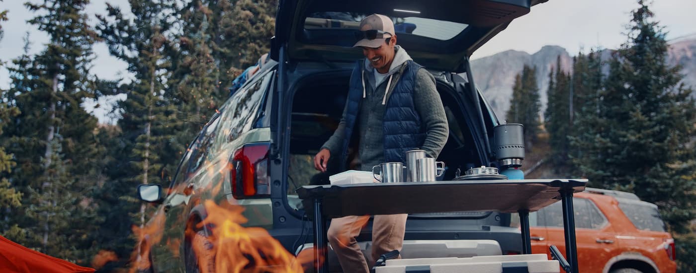 Man next to a table and green 2026 Honda Passport at a campsite