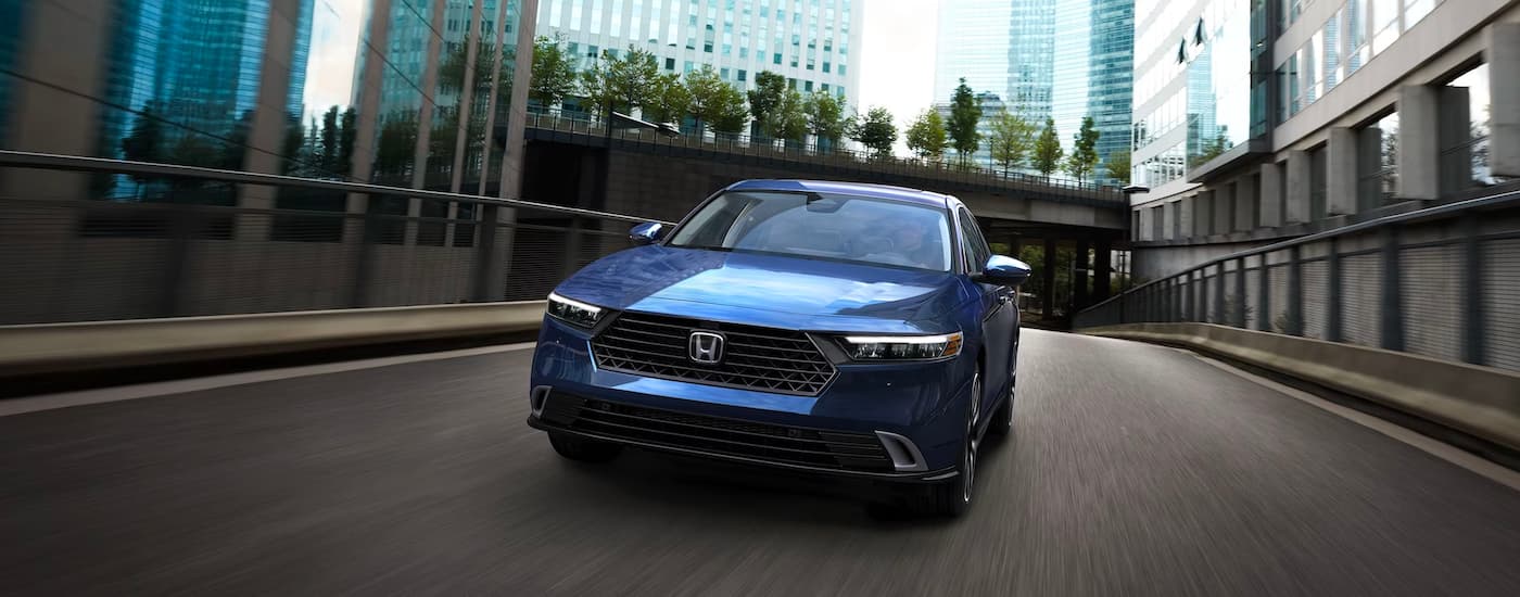 A blue 2024 Honda Accord Touring Hybrid driving across a bridge.