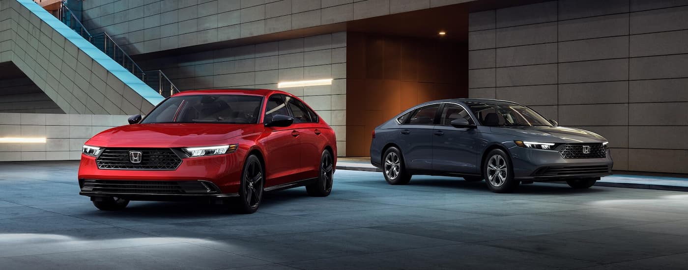 A red and a grey 2025 Honda Accord parked at night