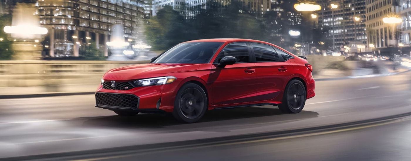 A red 2025 Honda Civic Si is shown driving to a Honda dealer.