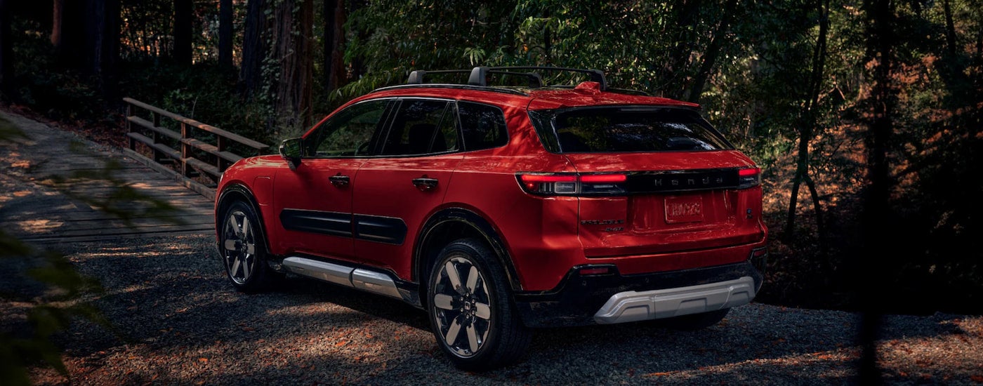 A red 2024 Honda Prologue Elite driving through the woods to visit a Honda dealer near Shelbyville.