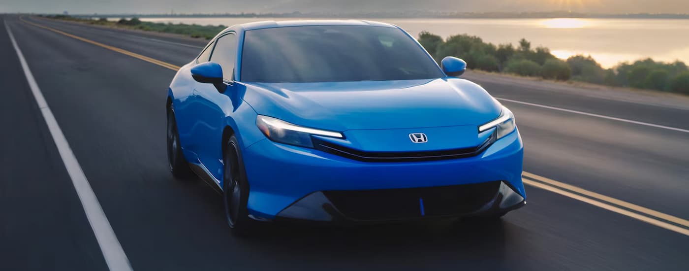 A blue 2026 Honda Prelude driving down a highway